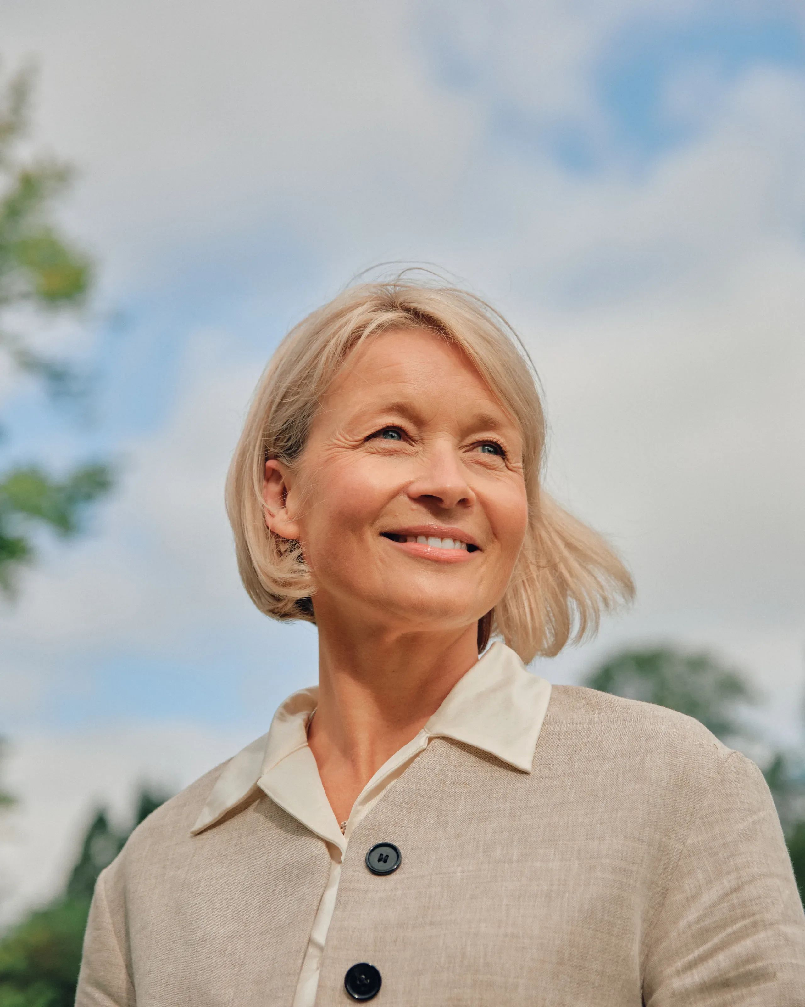 Eldre kvinne smiler utendørs.